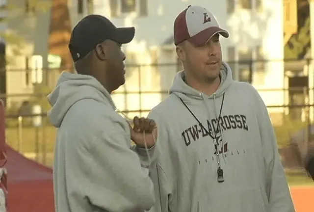 Two football coaches talking in a gym