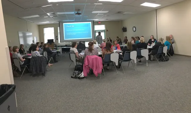 Large group gathered around tables for a training session