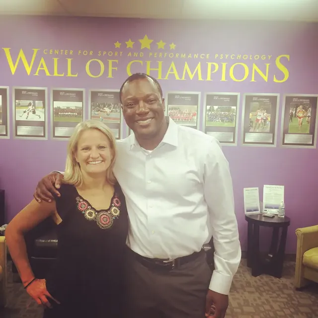 Kevin and a guest in front of a Wall of Champions display
